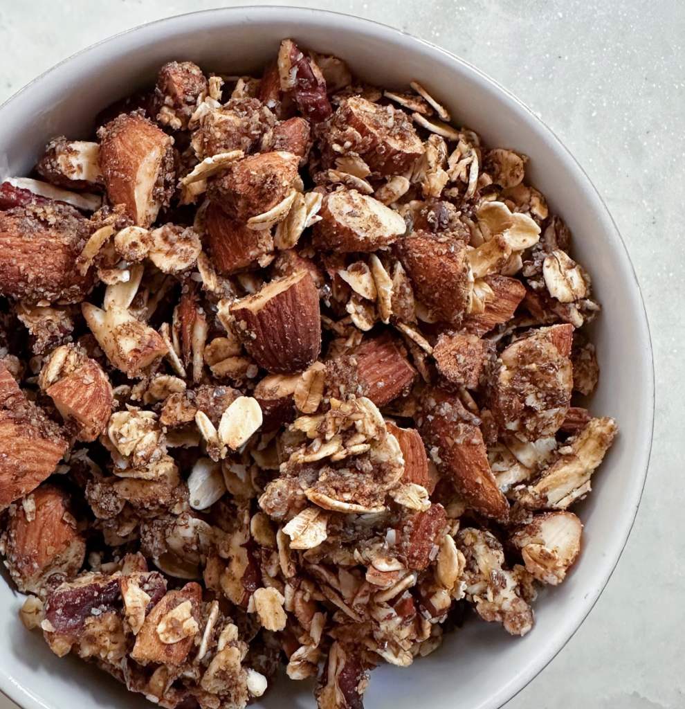 Bowl of homemade vegan granola on a white marble background