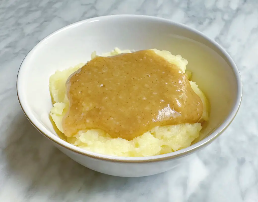 A small bowl of mashed potatoes covered in the finished homemade vegan gravy