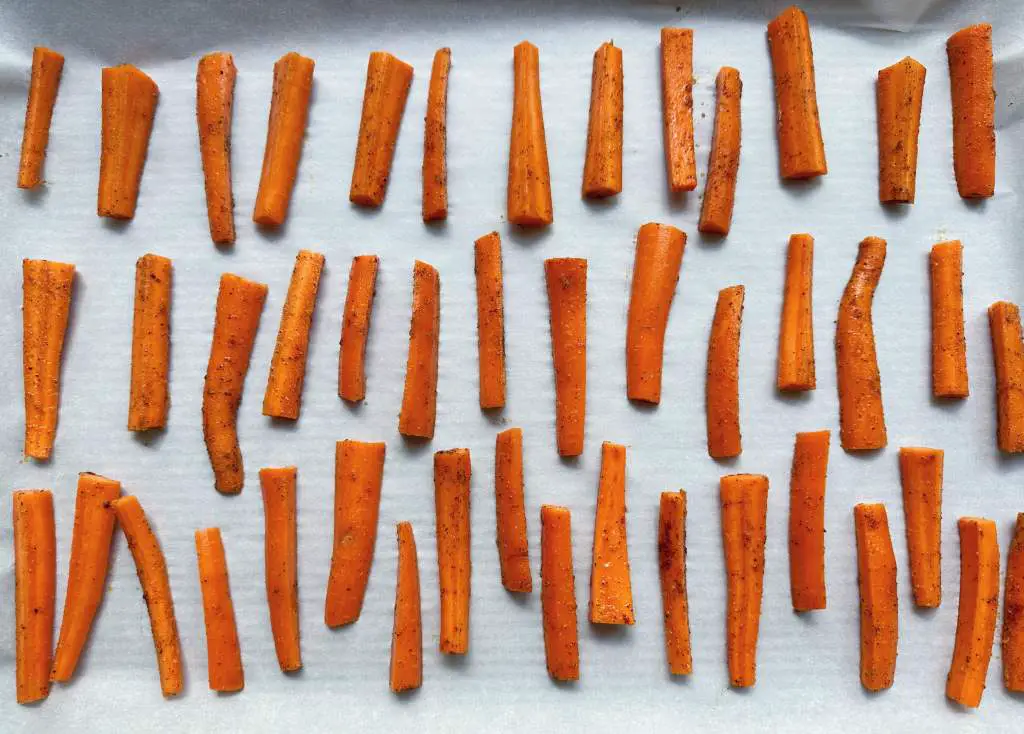 Carrot fries evenly spaces on parchment paper