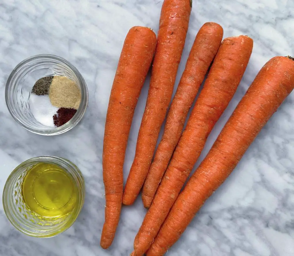 Carrots, spices and olive oil on a white marble background