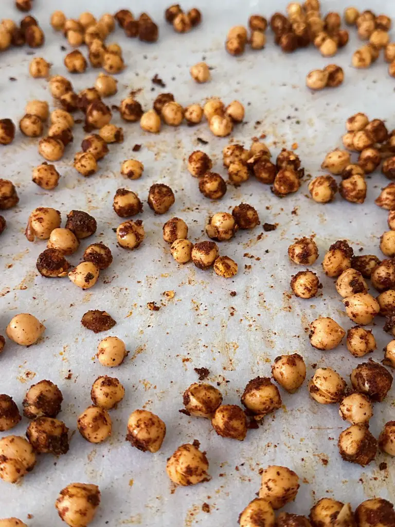 Crunchy baked chickpeas spread on a parchment-lined baking sheet.