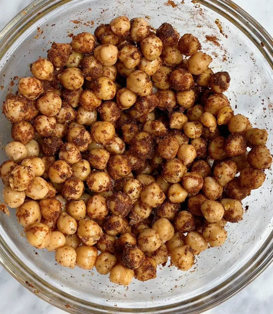 Bowl of unbaked chickpeas coated in taco seasoning and olive oil.