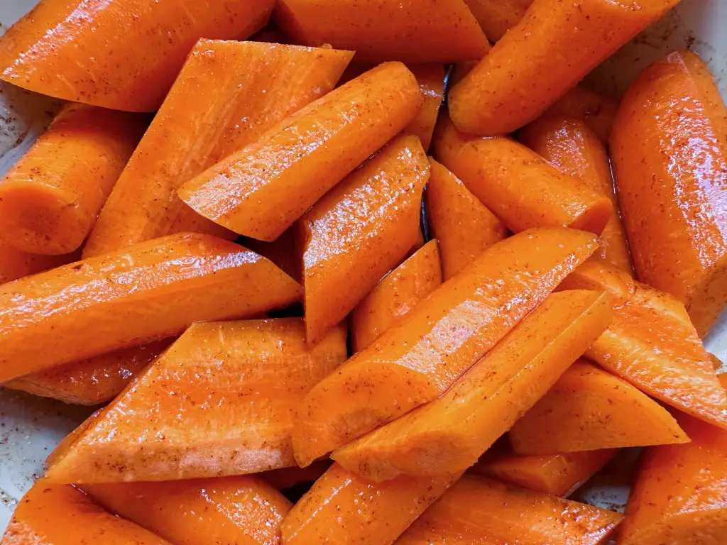 Close up of chopped carrots coated in spices and maple syrup