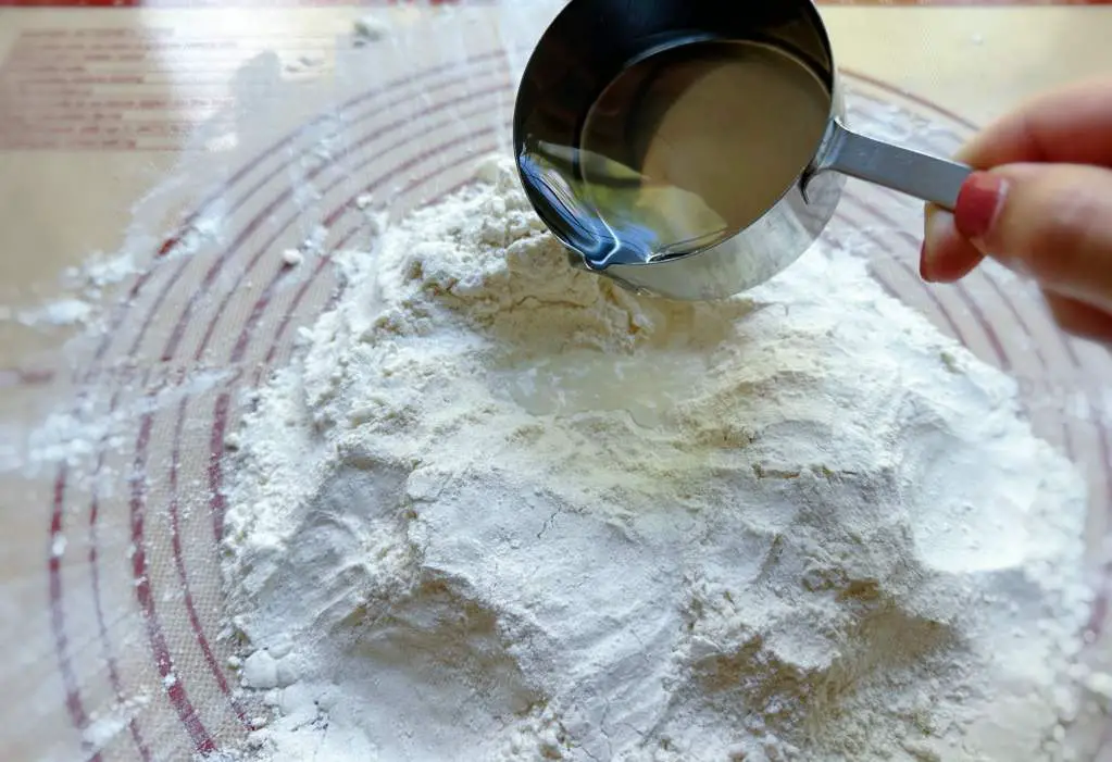 Pouring water into a well made in the center of the flour