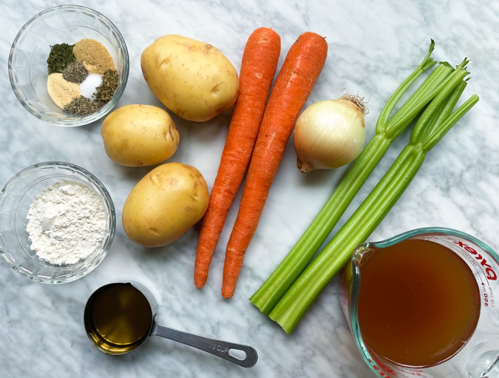 All ingredients for vegetable pot pie on white marble background