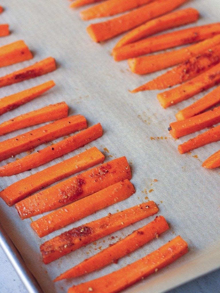 Carrot fries evenly spaces on parchment paper