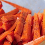 carrot sticks coated in oil and spices before cooking