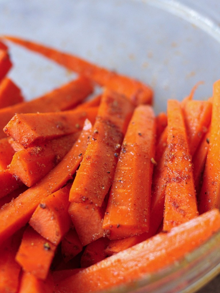 carrot sticks coated in oil and spices before cooking