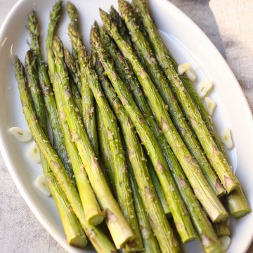 finished baked garlic roasted asparagus on a white plate