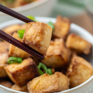 crispy sesame tofu close up being held by chop sticks