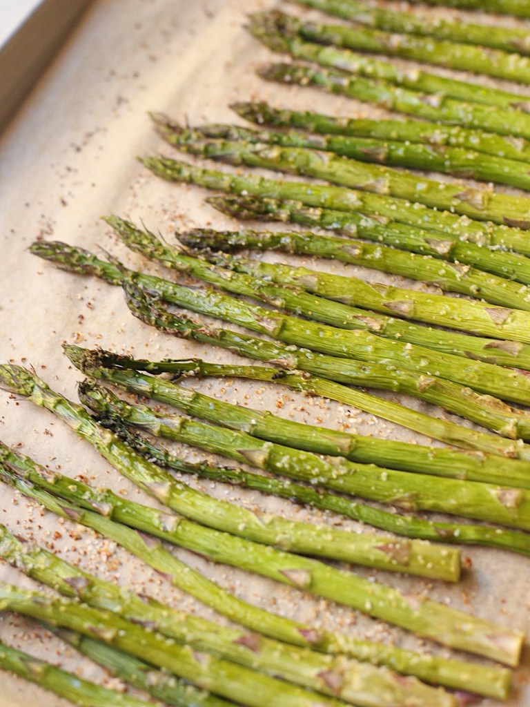 finished baked garlic roasted asparagus on a parchment-lined baking sheet
