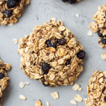 Finished healthy oatmeal cookies surrounded by oats on grey surface