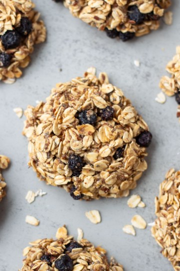 Finished healthy oatmeal cookies surrounded by oats on grey surface