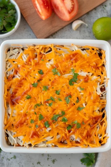 top view finished vegan mexican casserole garnished with enchilada sauce and herbs