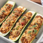 close up finished stuffed zucchini in a baking dish