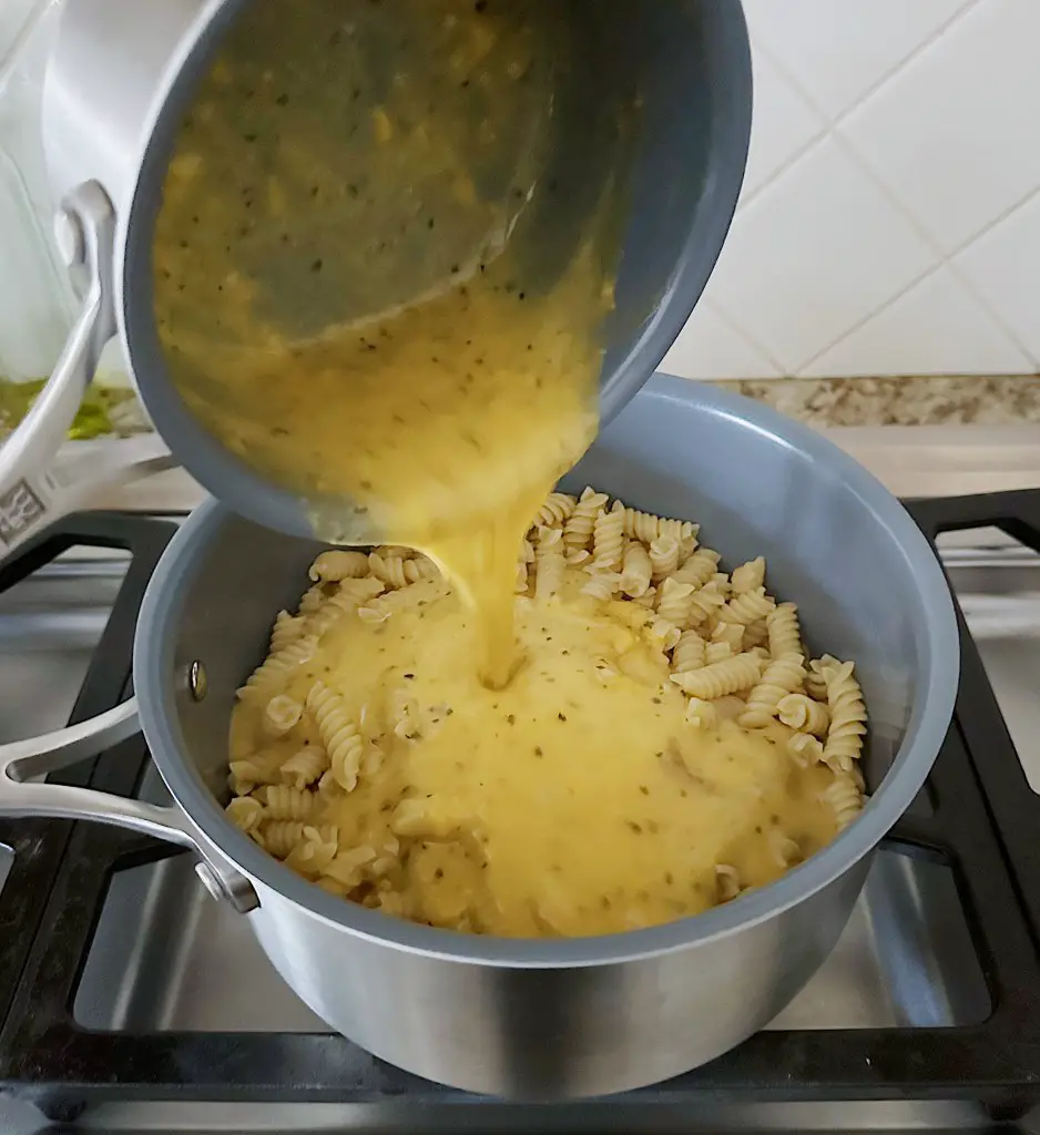 Pouring cheese sauce onto finished noodles
