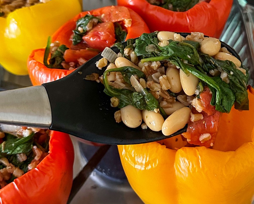 Scooping prepared filling into the cooked peppers