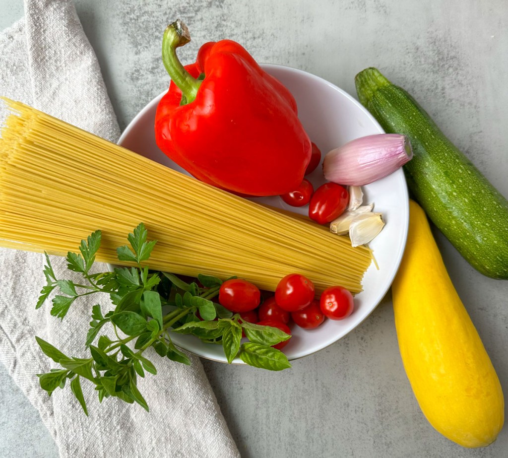 ingredients for vegan pasta primavera on grey background