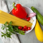 ingredients for vegan pasta primavera on grey background