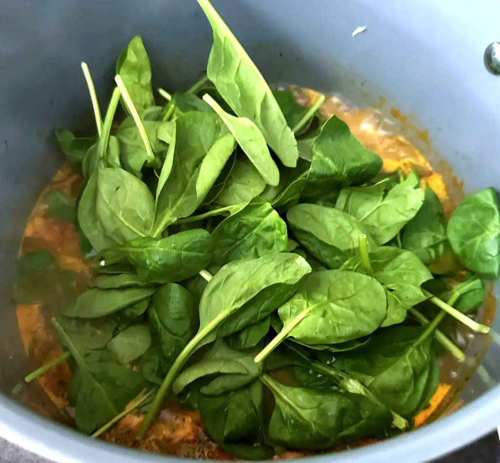 Fresh spinach being added to the soup