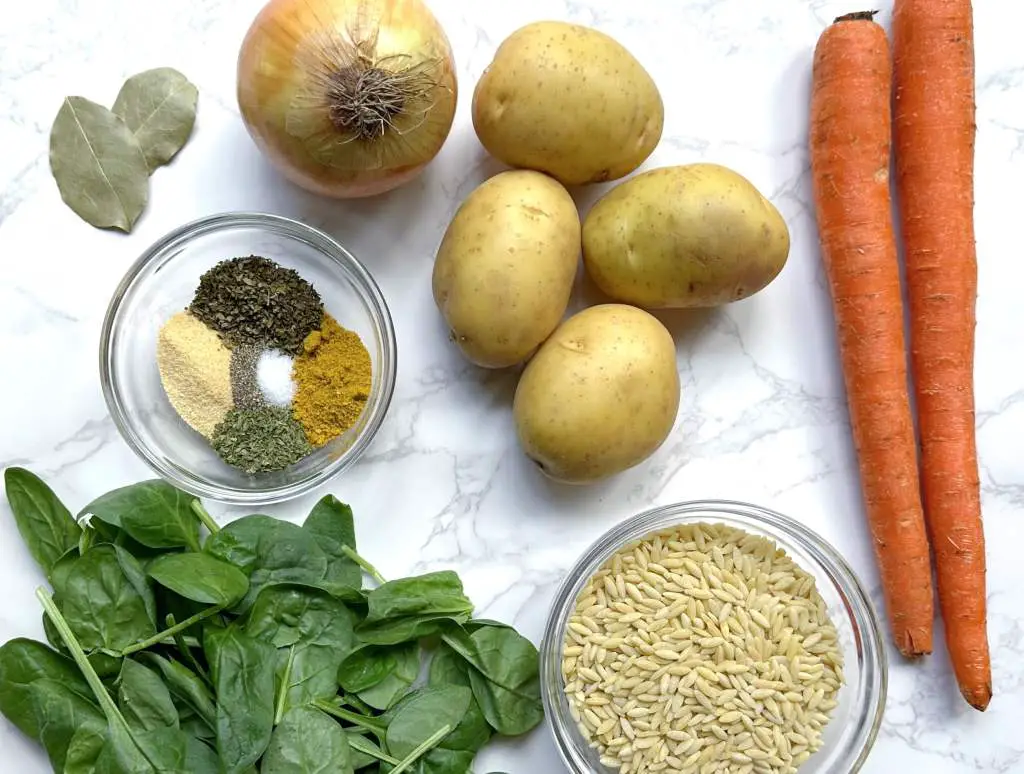 Ingredients to make spinach and potato soup on a white marble background