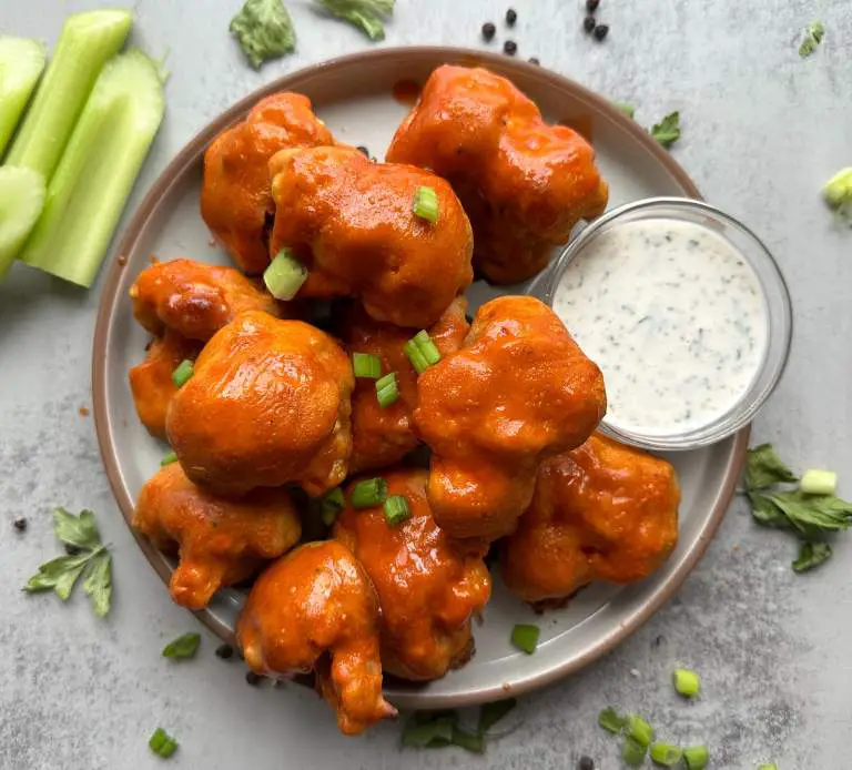 Finished plate of vegan buffalo cauliflower wings with ranch dressing