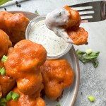 Finished vegan buffalo cauliflower wings dipped in vegan ranch