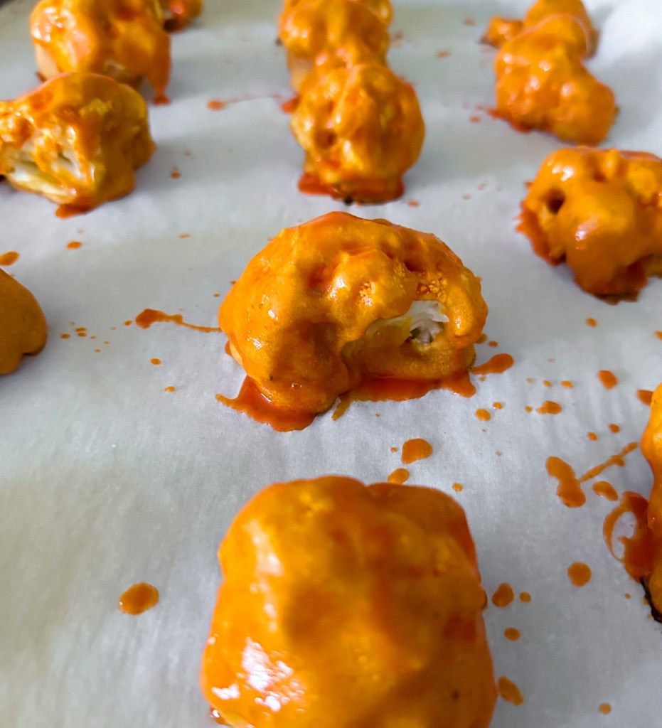 Cauliflower wings after first bake with sauce spread on them