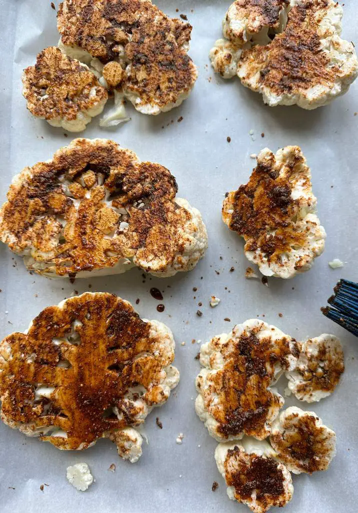 cauliflower steaks coated in spices on a baking sheet