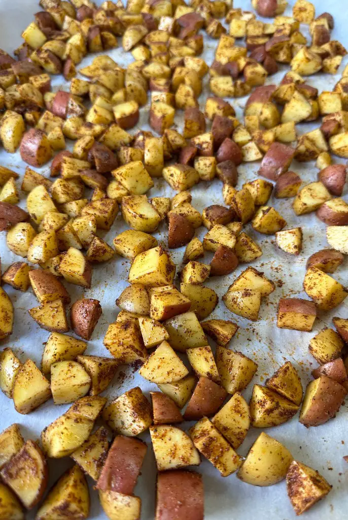 Uncooked vegan breakfast potatoes spread on a baking sheet