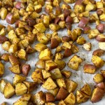 Uncooked vegan breakfast potatoes spread on a baking sheet