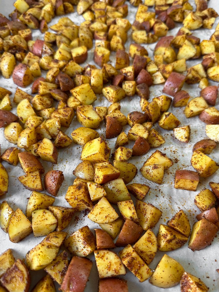 Uncooked vegan breakfast potatoes spread on a baking sheet