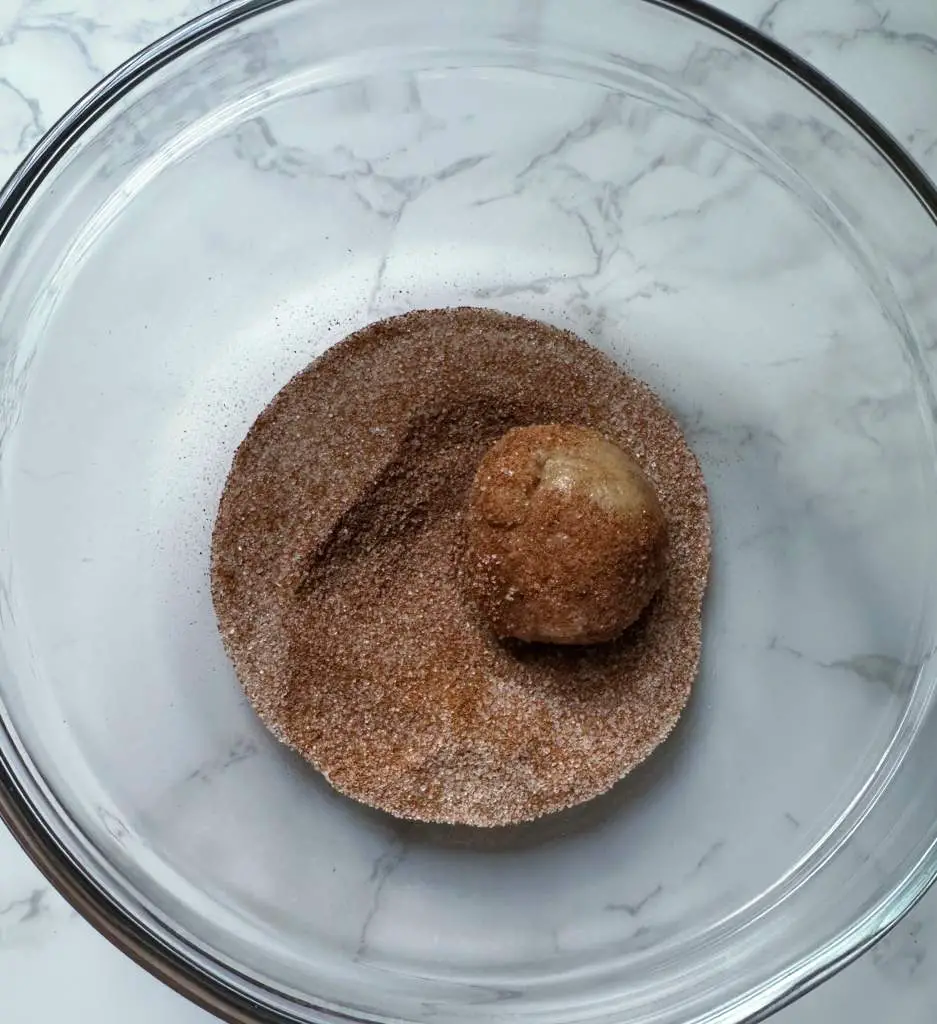 Ball of vegan snickerdoodle dough in cinnamon sugar coating