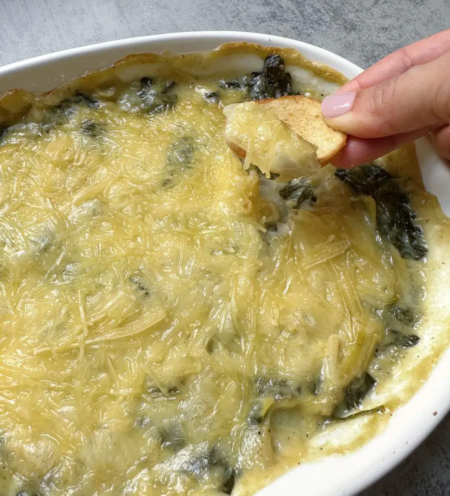 Using a chip to scoop some of the finished vegan spinach artichoke dip