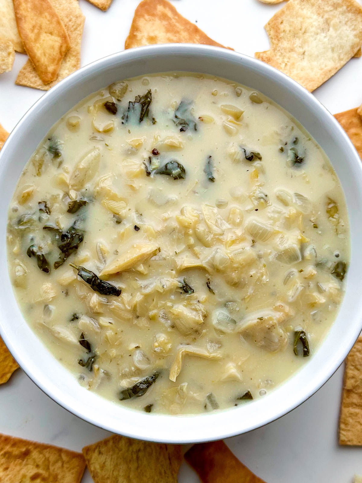 top view of a white bowl with vegan spinach artichoke dip
