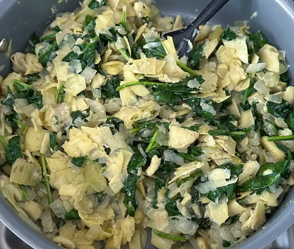 Spinach, artichoke and onions in a large saute pan