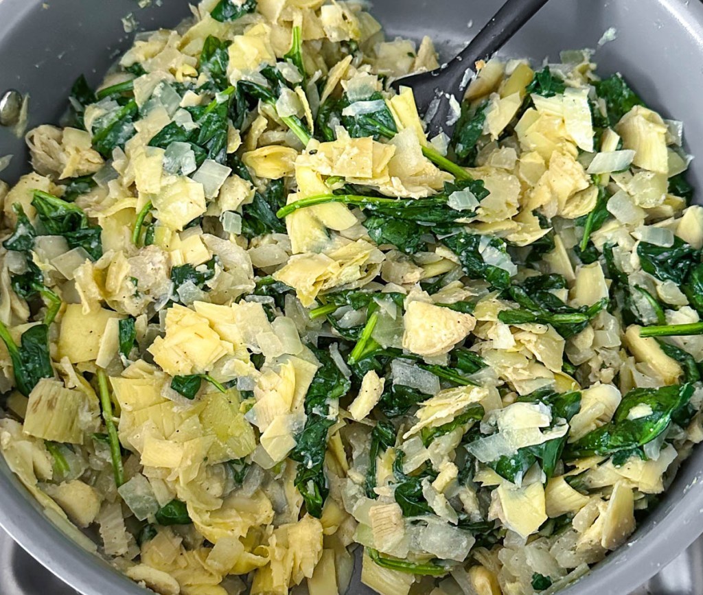 Spinach, artichoke and onions in a large saute pan