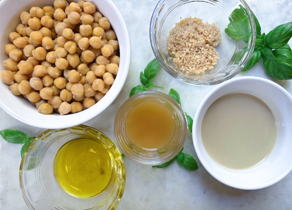 ingredients for lemon basil hummus on white marble background