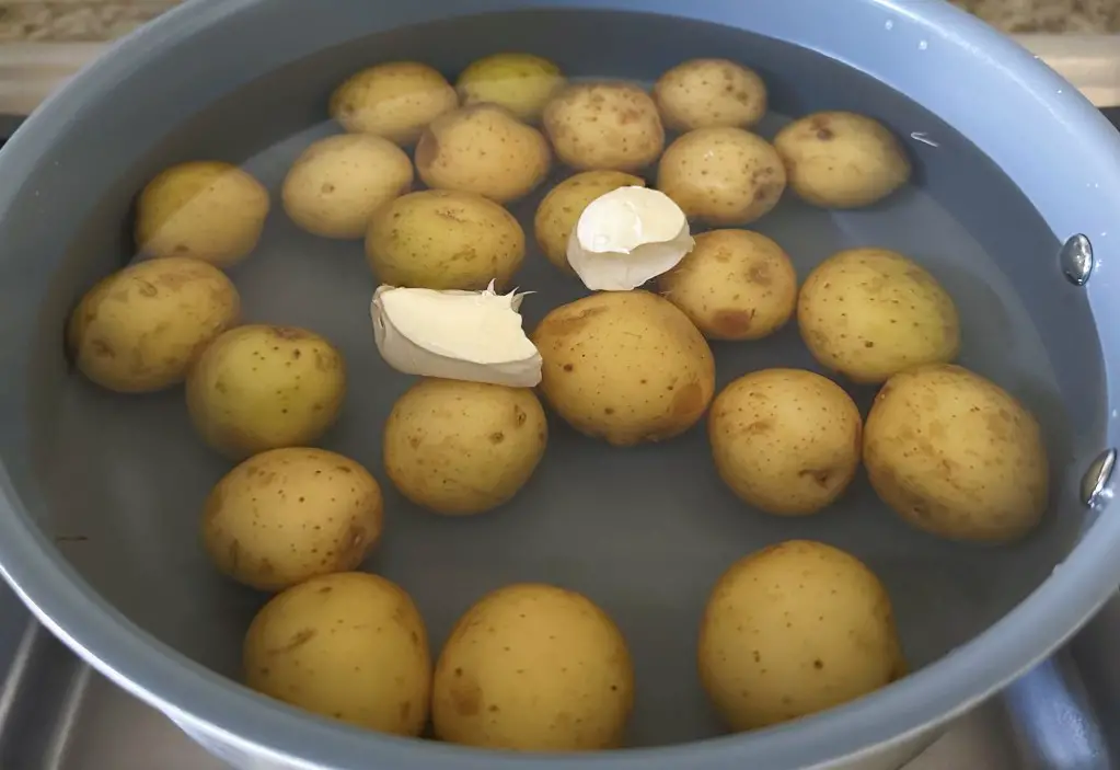 Baby potatoes covered in water in saute pan with butter