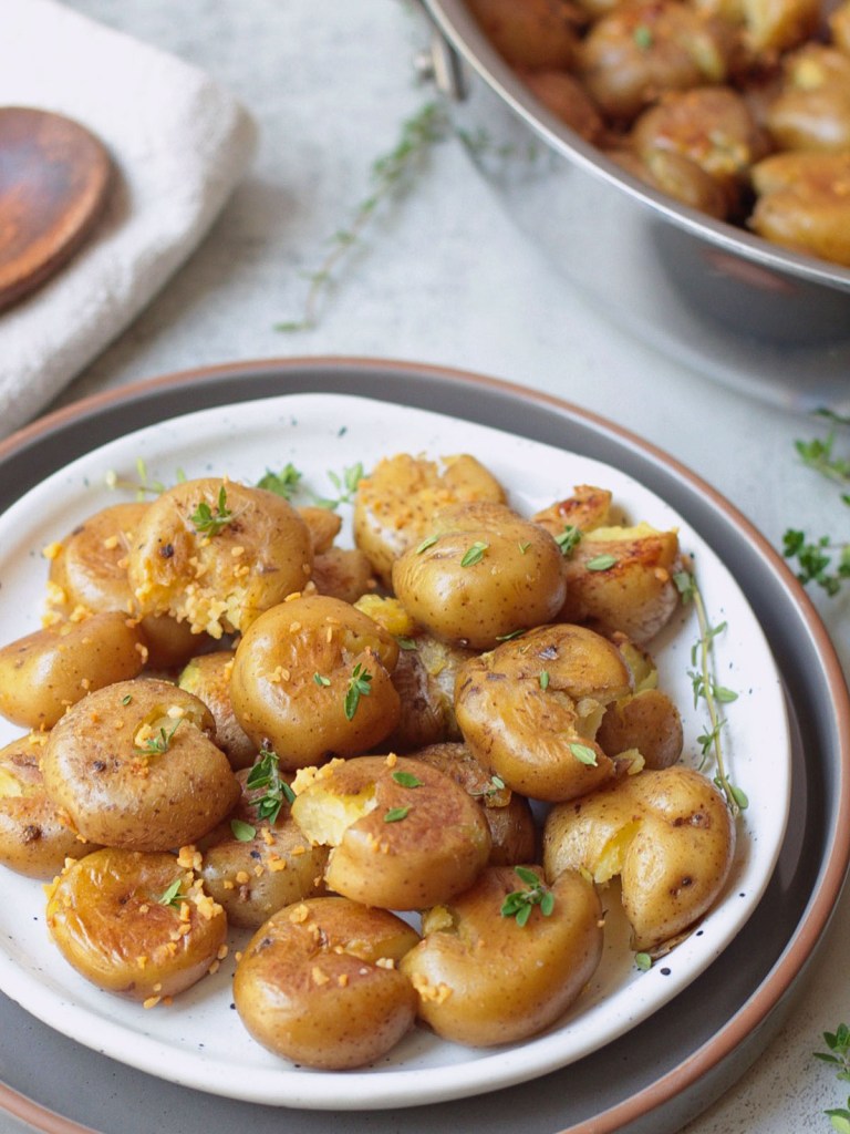 Crispy garlic smashed new potatoes on a white plate