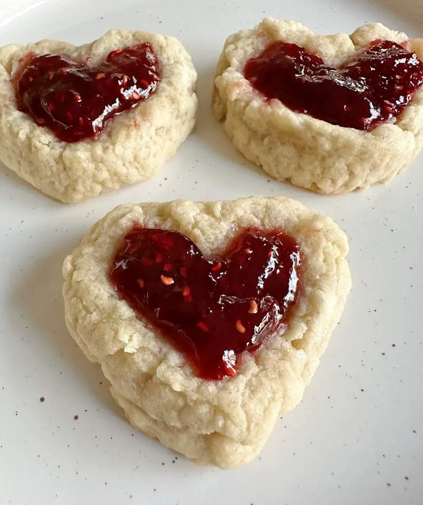 3 finished raspberry thumbprint cookies in the shape of a heart