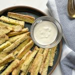 finished air fryer zucchini fries on a plate with a side of ranch dressing.