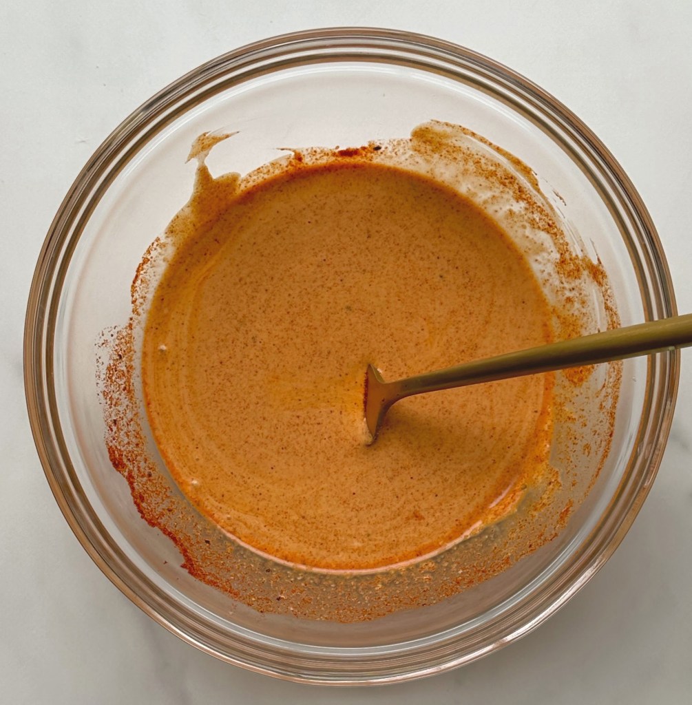 vegan chipotle lime aioli in a glass bowl after being mixed with a fork