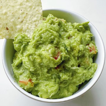 easy homemade guacamole with chip dipping from white bowl