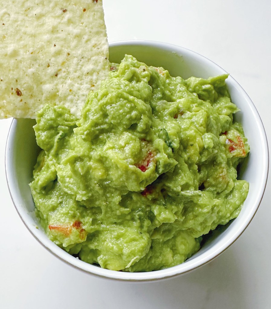 easy homemade guacamole with chip dipping from white bowl