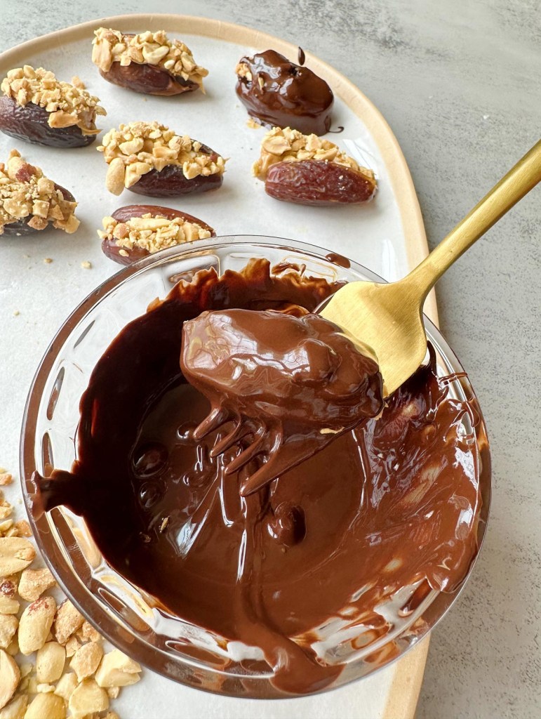 stuffed date being dipped in chocolate before freezing
