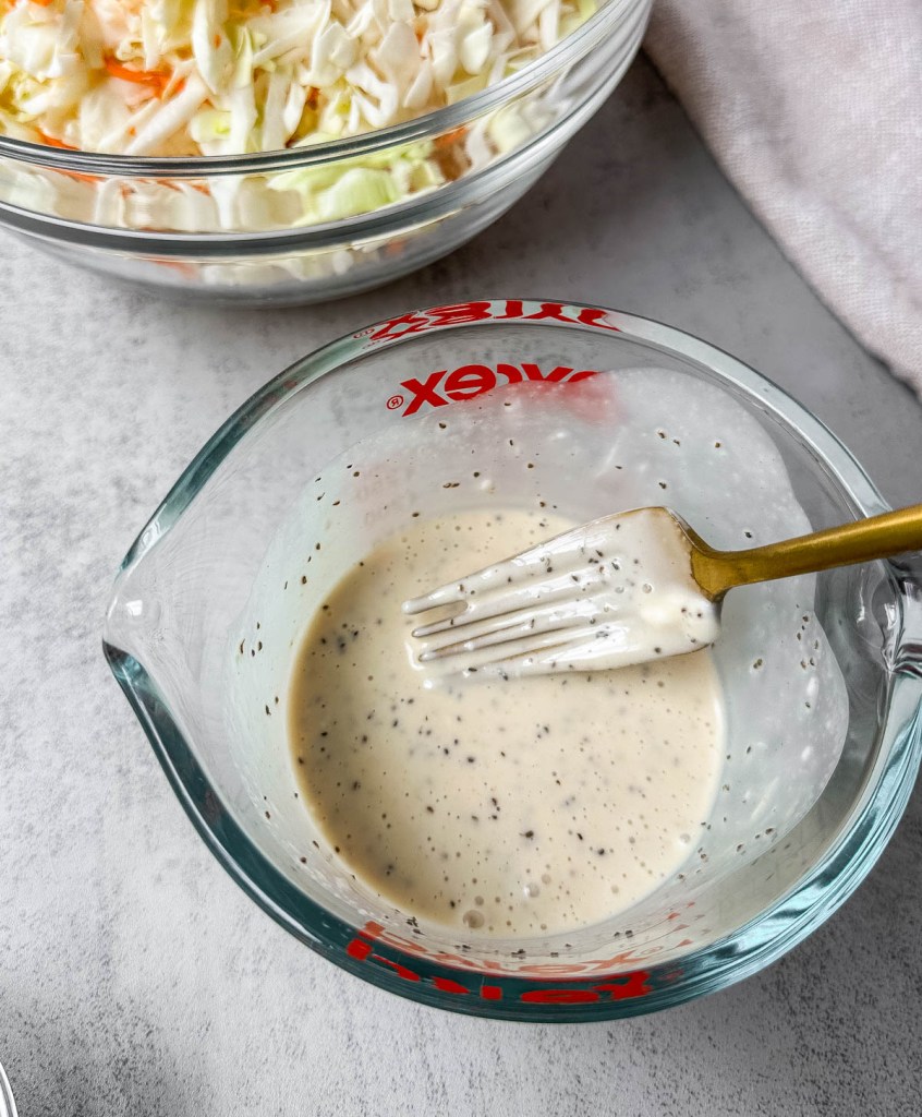 vegan coleslaw dressing being mixed with a fork