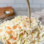 vegan coleslaw dressing being poured onto cabbage mixture