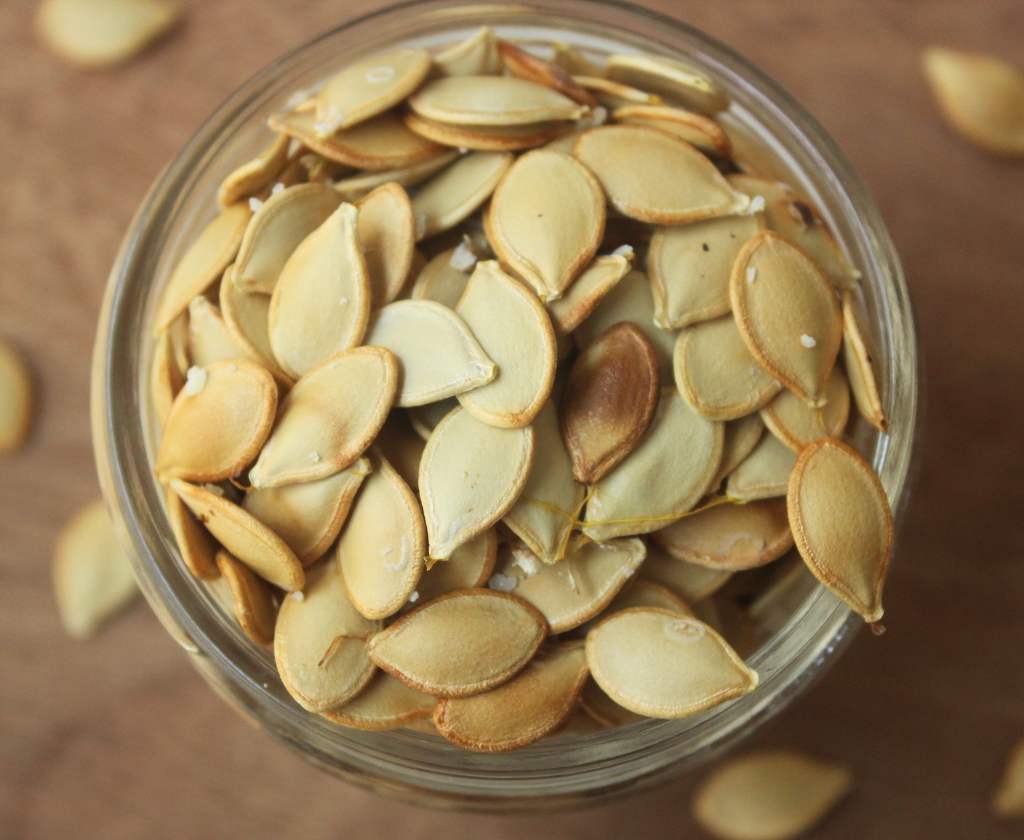 roasted acorn squash seeds in a small glass container