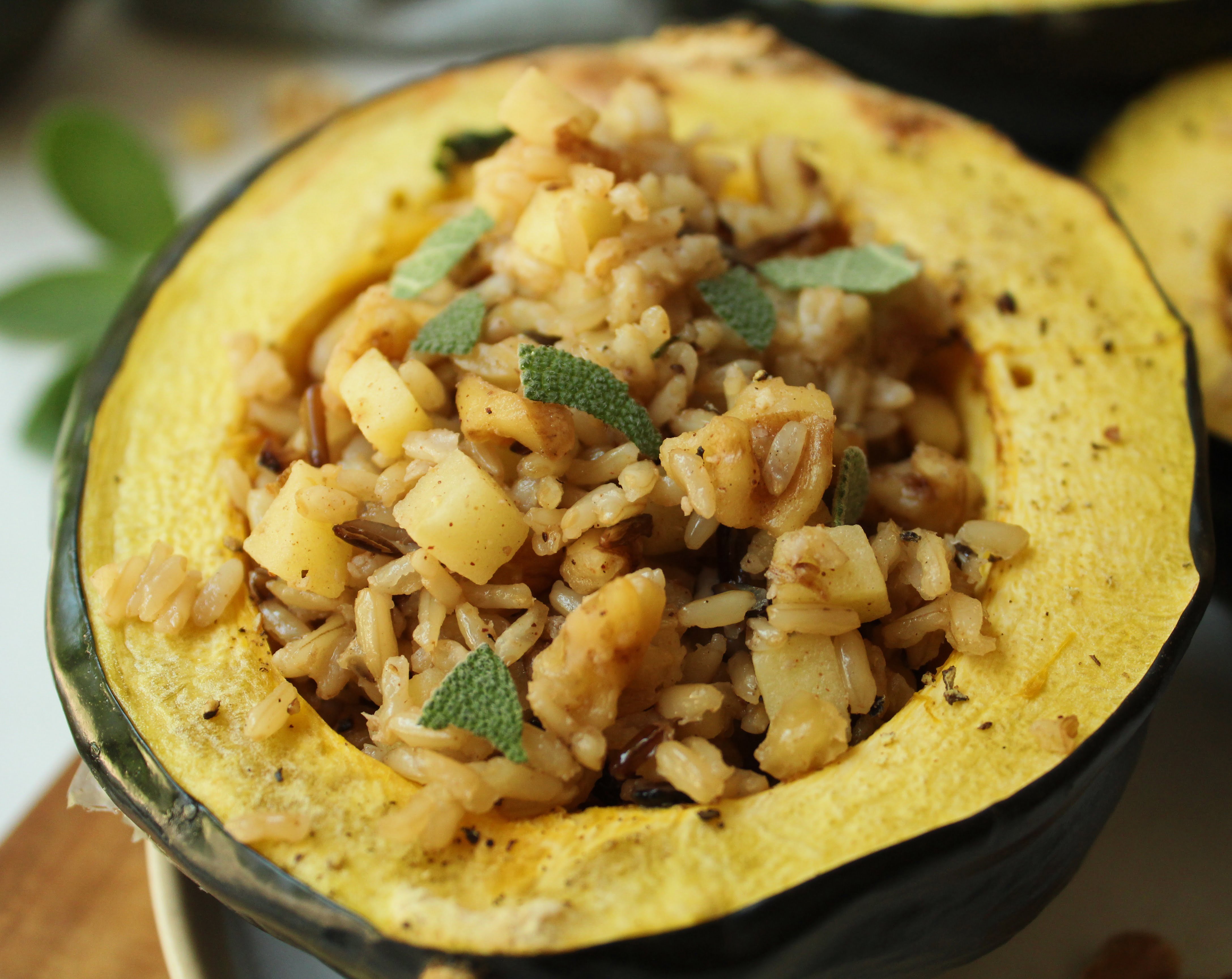 Vegan stuffed acorn squash with wild rice close up topped with sage